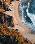 A clifftop view of waves breaking on the a beach below the famous Bixby Creek Bridge in crystal clear water on the the Big Sur Californian coastline at sunset