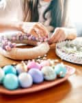 Close-up of women's hands making a wreath of eggs for Easter.