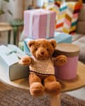 Teddy bear with gifts arranged on coffee table for baby shower party