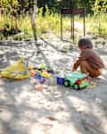 Nature's Playground: Toddler Boy Immerses in Sand Play by the Forest House