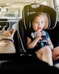 Toddler and baby in car seats in back of car