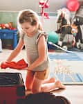 Little girl packing suitcase at home. Cute child putting clothes into suitcase. Preparing for family vacations with children. Practicing independence