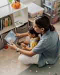 Mid adult woman reading a picture book to her son in the playroom
