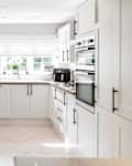 A general interior view of a new white fitted kitchen with black handles