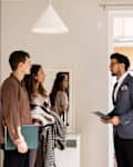 Salesman discussing with male and female clients while standing at home