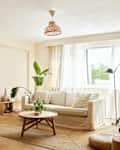 Empty sofa in front of coffee table. Interior of living room with plants and decor. Furniture at home.