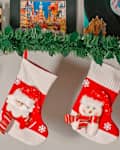 Three festive Christmas stockings hang from a garland, featuring a polar bear, Santa, and a snowman design.