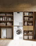 Modern Laundry Room With Washing Machine, Dryer, Laundry Basket And Folded Towels In The Cabinet