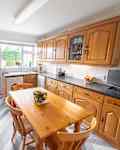A general interior view of an oak country rustic style fitted kitchen with dining table and chairs