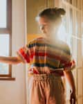 A little girl stands in a sunny room in a residential home, playing with a doll figure
