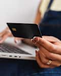 Close up view of young African American woman using her laptop and credit card to make an online payment. E-commerce and online shopping concept