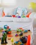 Colorful chaos fills a cozy living room as a young child looking a digital tablet