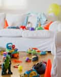 Colorful chaos fills a cozy living room as a young child looking a digital tablet