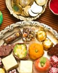 Diwali festive preparations with a plate of sweets ,diyas,money,kumkum and haldi.