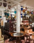 photo of antique and vintage furniture store interior. Lots of different tables, dressers, chairs, etc. Hanging different-colored pendant lights for sale