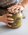 Someone opening jar of pickled cucumbers