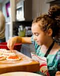 Mixed race girl cooking in kitchen