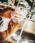 Close view of man washing glass in the kitchen.