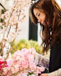 Woman working in flower shop trimming branches with blossoms and flowers