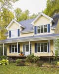 Yellow clapboard with blue and white trim cottage style home facade in autumn, Quebec, Canada.