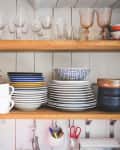 Crockery and drinking glasses on shelves in kitchen at home