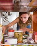 women reaching in orange cabinet for pantry items