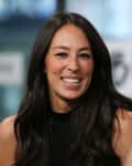 A woman with long dark hair smiling, wearing a black sleeveless top, in a conversation.