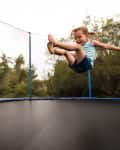 Little girl enjoying as she jumps on trampoline bed