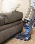 Legs of Caucasian man vacuuming rug near sofa