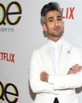 Person in a white suit at a Queer Eye and Netflix event backdrop.