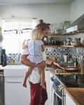 Mid adult father carrying daughter while cooking food in kitchen