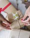 Hands tying the bow on a Christmas present
