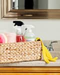 Wicker basket of cleaning supplies on top of bathroom sink