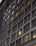 Generic exterior evening time establishing shot outside office or apartment building with large windows and lights illuminating rooms inside. Setting for any large city urban loft highrise in USA