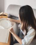 A person unpacking a dish from a box filled with paper