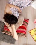 Two people lying on the floor on cushions and playing a board game