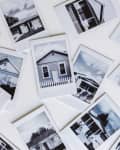 Scattered black and white Polaroid photos of various houses with different architectural styles.