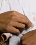 man using a gray towel to blot a brown-colored stain on a white button-up shirt