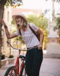 Positive and happy girls walking on the city street with bicycles. Female friends enjoying a walking down the street with their bikes.