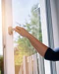 woman opens a window with a mosquito screen
