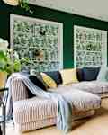 Modern and cozy living room with corduroy sofa, coffee table, plants and big window to the garden. Bright and sunny family space.