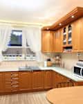 Outdated kitchen with ambered wood cabinets and ruffled white curtains