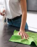 Close up of a young woman cleaning kitchen with detergent.