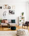 Stylish beige armchair and pouf on the cozy carpet in classy living room interior with grey settee and vintage furniture.