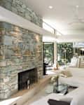 Sunken seating area and stone fireplace with dining area in background at home