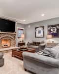 ELMHURST, IL, USA - JANUARY 30, 2020: A man cave, living room with a television mounted above a lit fireplace and football jerseys mounted on the wall.
