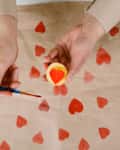 heart shaped potato stamp on craft paper. The process of decorating a gift for Valentine's Day. Getting ready for the celebration on February 14th.