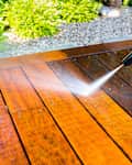 cleaning the terrace with a pressure washer - high-pressure cleaner on the wooden surface of the terrace - very shallow depth of field - sharpness on the terrace board under a stream of water