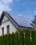 Solar panels on a gable roof. Beautiful, large modern house and solar energy. Rays of the sun.