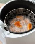 Modern home deep fryer with nuggets and french fries on table in kitchen